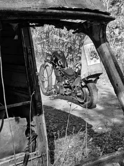 Purple chopper seen through the window of a rusted vehicle